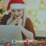 Woman happily looking at her laptop whilst sitting in a Christmas setting