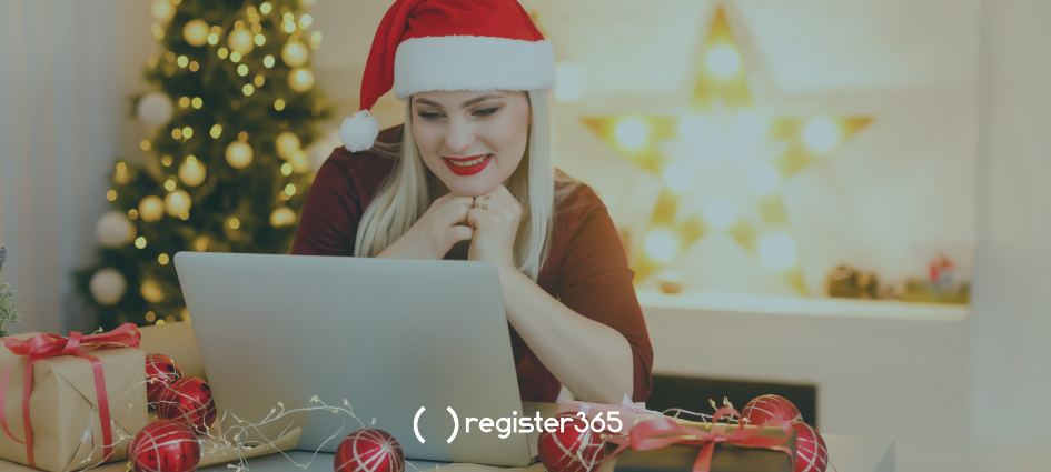 Woman happily looking at her laptop whilst sitting in a Christmas setting